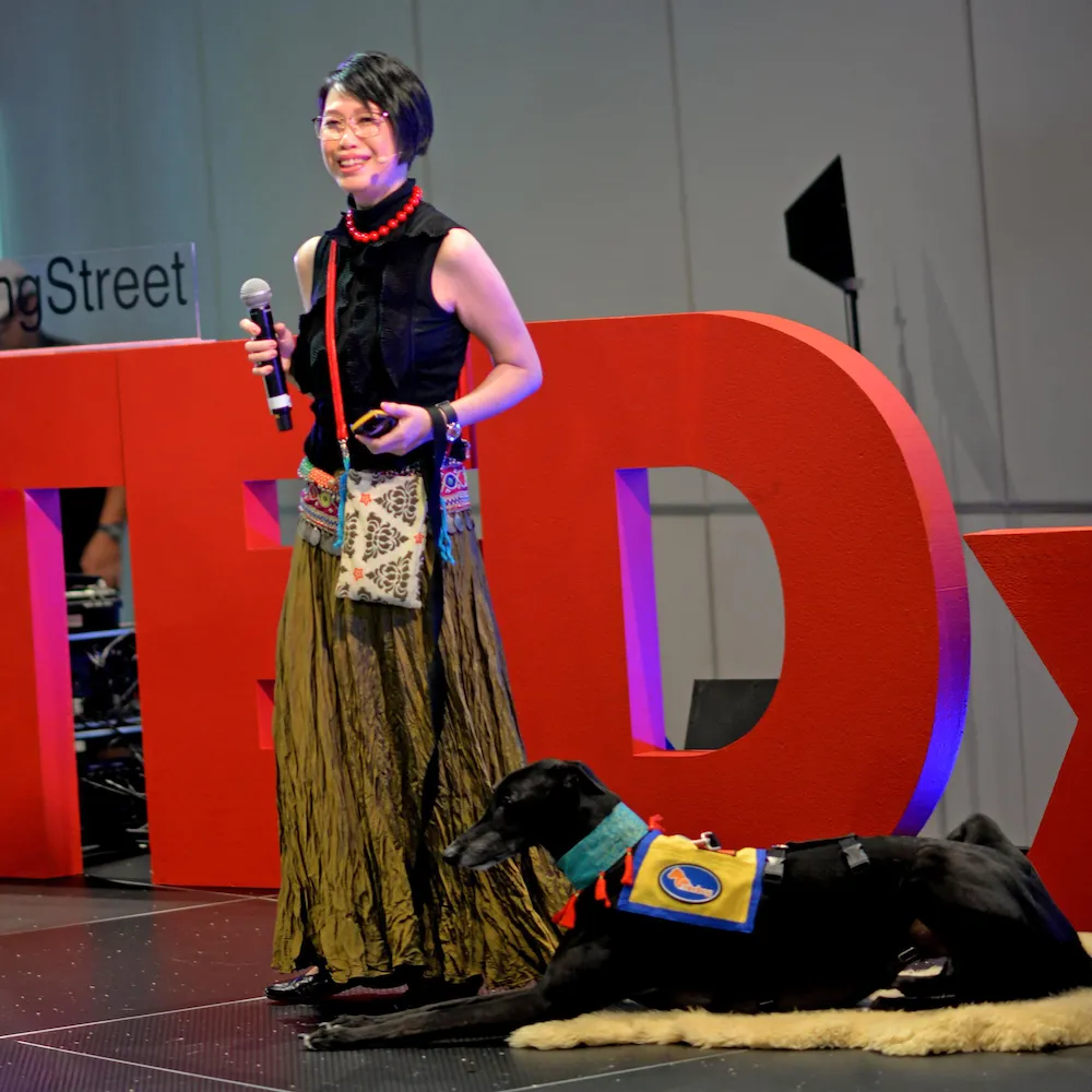 Dr Dawn speaking at her event, with her assistance dog by her side